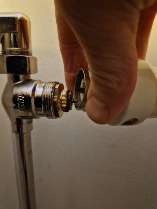 En hand monterar termostat på radiatorventil, närbild, inomhus, uppvärmning, underhåll, energieffektivitet.