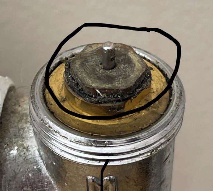 Förstorad bild av en mekanisk detalj; metall, slitage, skruv, möjlig cirkulär markering med svart penna.
