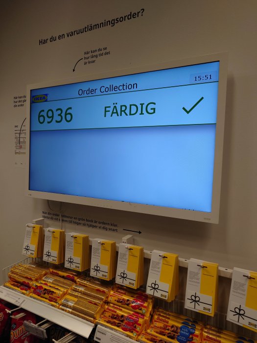 Digital skärm visar '6936 FÄRDIG' hos IKEA, svensk text, godis och snacks nedanför.