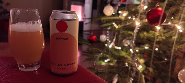 Ölglas och burk framför julgran med prydnader och ljusslingor. Inomhus, mysig stämning, högtidsfirande.