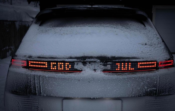 En bil täckt av snö visar bakljus och modellnamn "IONIQ 5" i skymningen eller gryningen.