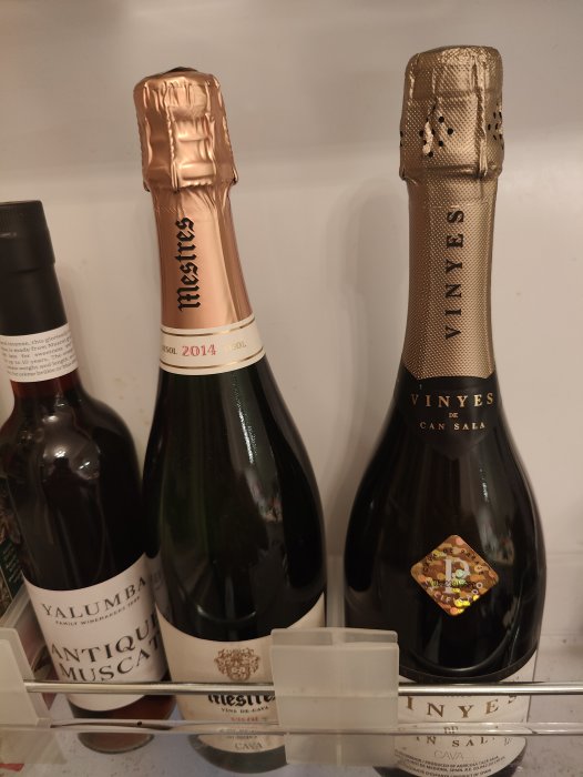 Två flaskor mousserande vin i kylskåp, en med rosa folie, en med guld, årgång 2014.