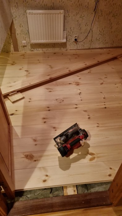 Golv under renovering med synlig isolering och elverktyg, i ett ogjort rum.