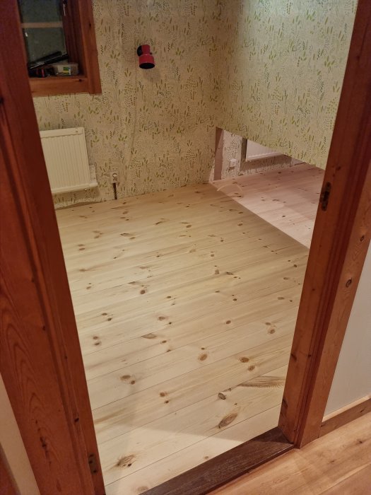 Trägolv, tomrum, tapetserade väggar, dörrkarm, inredningsarbete pågår, renoverat rum, inomhus, bostadsutrymme.