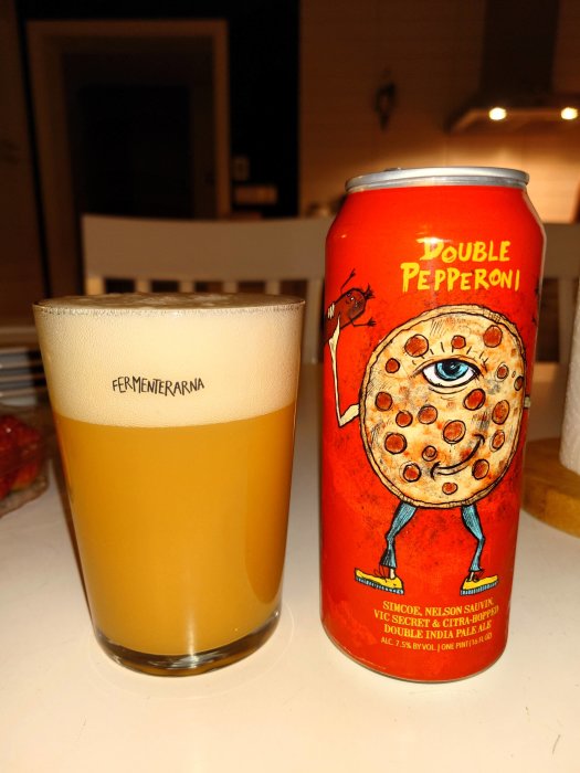 Ett ölglas med skum och en färgglad burk med tecknad pepperoni-pizza karaktär, "Double Pepperoni" etikett.