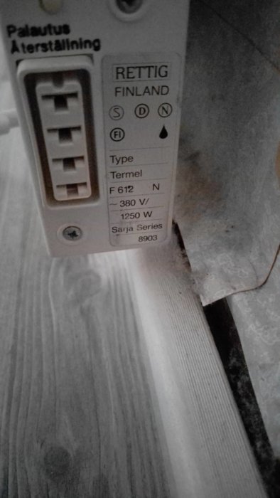 En väggmonterad enhet med etikett och inställningar, sannolikt en radiator eller uppvärmningssystemskomponent. Made in Finland.