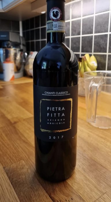 Flaska Chianti Classico rödvin, årgång 2017, köksbänk, frukt i bakgrunden.