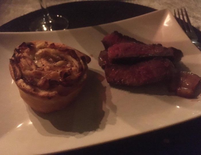Middag på restaurang: biff, tarte, mörkt ljus, vinglas, minimalistisk presentation, matfotografi.