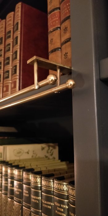 Gammaldags bokhylla med inbundna böcker och en mässingslampa i klassisk stil.