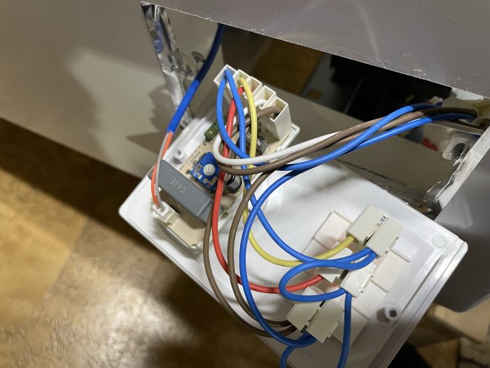 Öppet eluttag med anslutna kablar och synliga anslutningsblock, installationsarbete, byggarbetsplats, oavslutat elektriskt arbete.