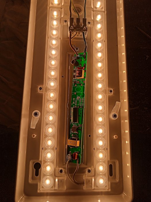 Inuti en LED-lampa: kretskort, upplysta dioder, kablar och metallstruktur. Elektronik och belysningsteknik kombinerade.