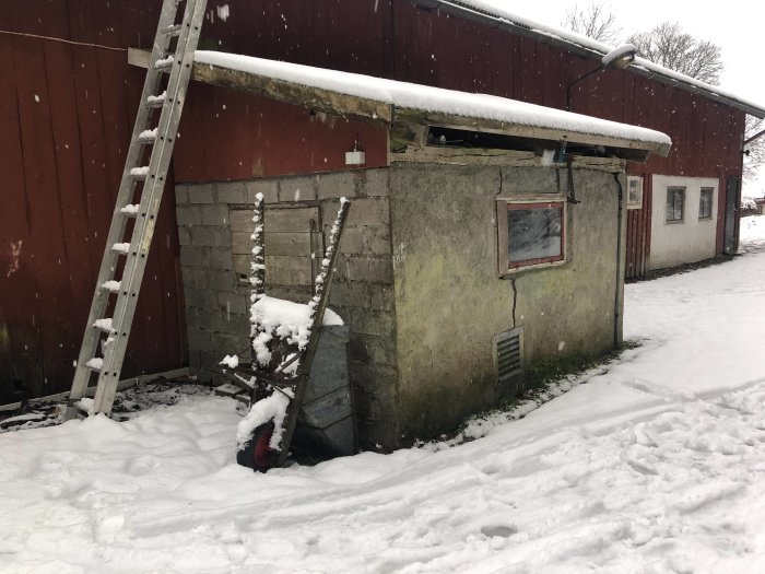 En gammal byggnad i snöigt landskap med stegar och gammalt verktyg.