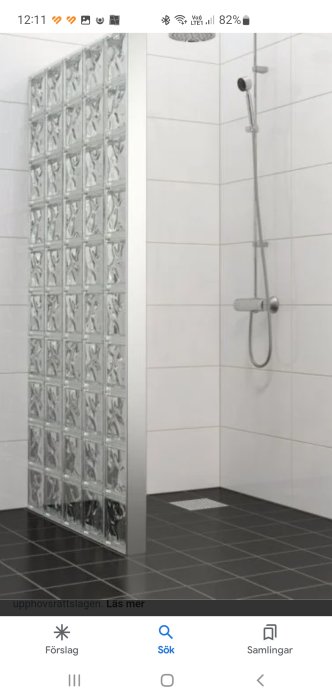 En duschhörna med glasblocksvägg och handhållen dusch i ett kaklat badrum.