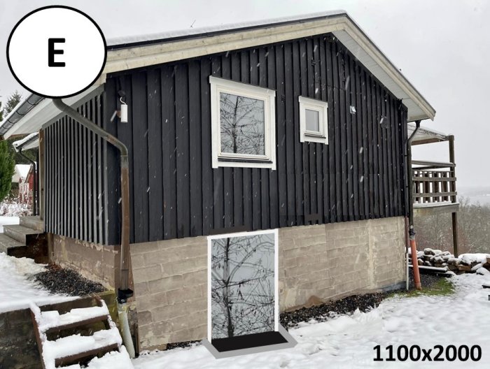 Svart trähus, snö, tillägg av dörrstorlek och energimärkning, vinterdag.