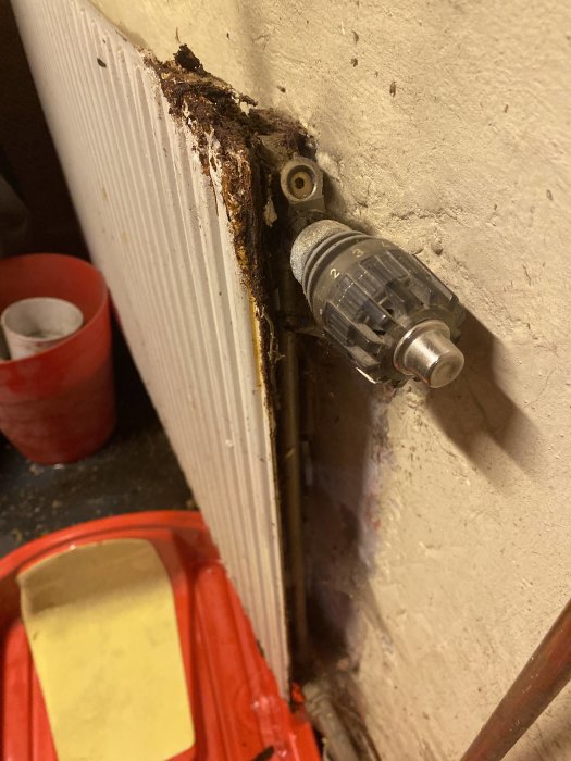 En elementtermostat med tecken på vattenläckage och rost på väggen bredvid. Behov av underhåll syns.