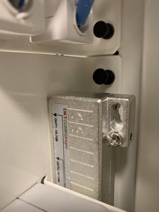 Ett frekvensfilter för kabel-TV monterat på vit vägg, med anslutande kablar och etikett.