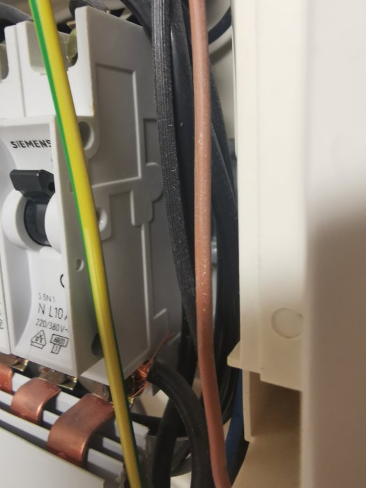 Elcentral med säkringar och ledningar, detaljbild på elektriska komponenter, märkt Siemens, kopparledare synliga.