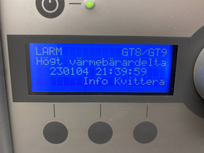 Digital display med blå bakgrundsbelysning visar text "LARM" och tid/datum-information på svenska.