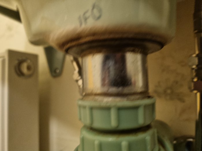 Närbild på en oskarp rörmokardetalj med texten "IFO", troligen i ett badrum eller kök.