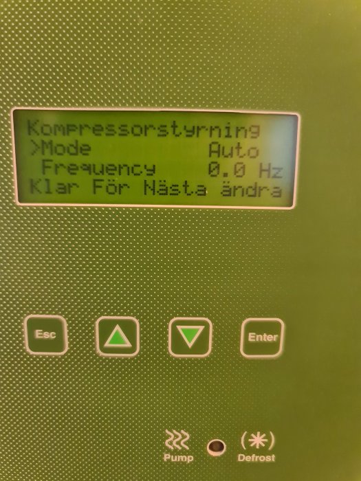 Digital display med texten "Kompressorstyrning", knappar och symboler för pump och avfrostning på grön bakgrund.