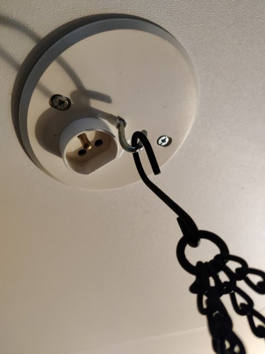 Takfäste med oanvänd elkabeluttag och svart sladd mot vit bakgrund.