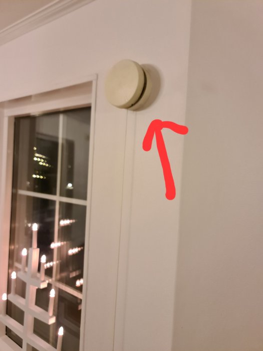 Vit vägg med fönster, brandvarnare, röd pil. Inomhus, kväll, ljust, enkelt.