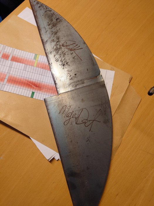Använd, smutsigt knivblad med inskriptioner, på ett bord med kuvert och papper.