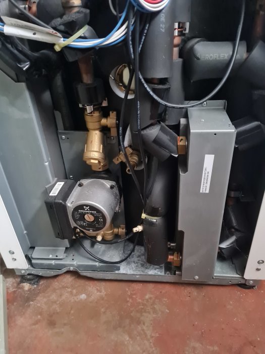 Invändig vy av en uppvärmningsanläggning med rör, ventiler och elektromekaniska komponenter.