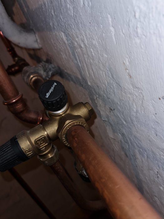 Bilden visar en termostatventil kopplad till kopparrör, troligen en del av en värmesysteminstallation.