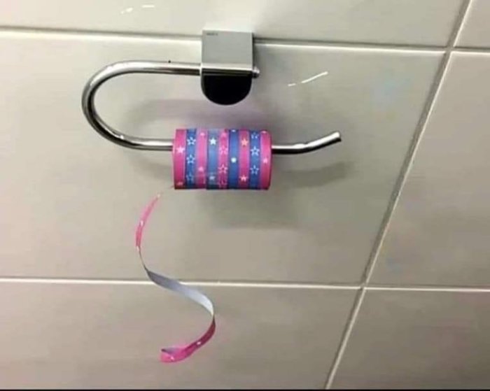 Hänglås fastsatt vid toalettpappershållare med dekorerat toapapper, humoristisk bild, konceptuell, leriga kakelväggar.