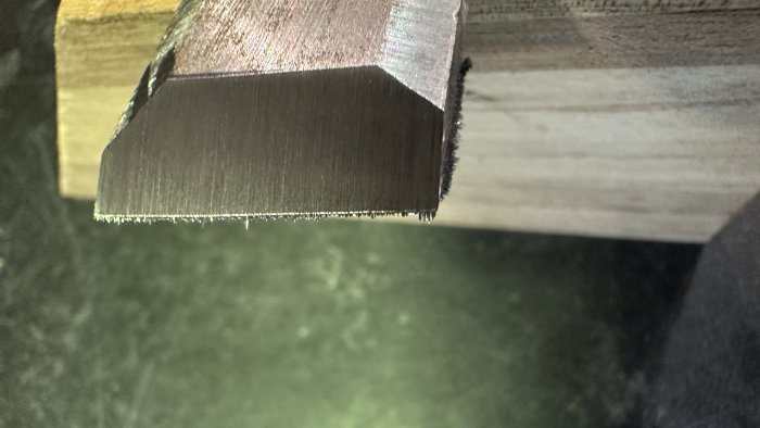 Närbild av sågat trä och metallprofil med sågspån; kontrast mellan naturliga och tillverkade material.
