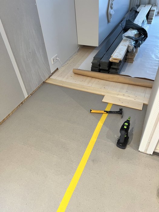 Golvinstallation pågår, träplankor, verktyg, gult markeringstejp, inomhus, renovering, otillgängliga området.