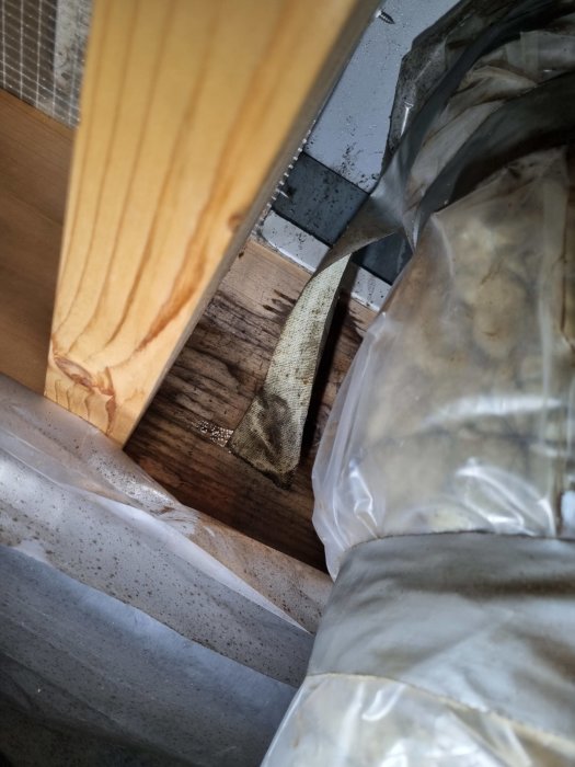 Översikt av en rörig, oorganiserad plats med trä, plast och smuts.