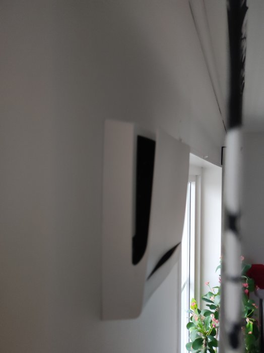 Inomhus, vita pappersark hängande i snören, oskarpt, bakgrund med gröna växter och fönster, diffust dagsljus.