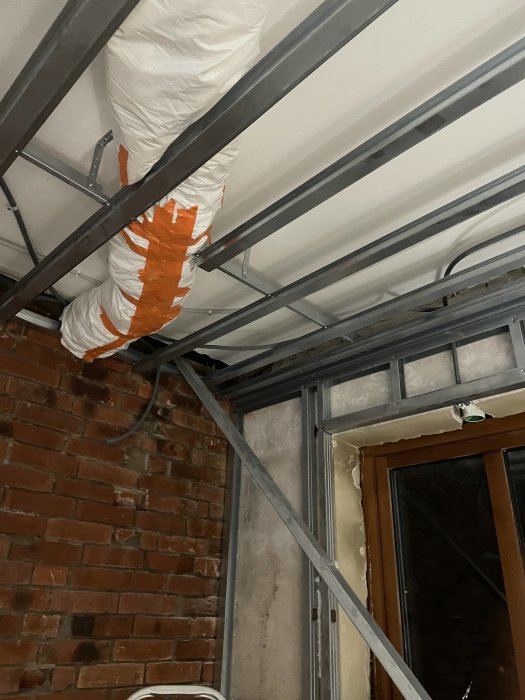 Ventilationssystem, metallstomme, tegelvägg, isolering, orange tejp, inomhus konstruktion.