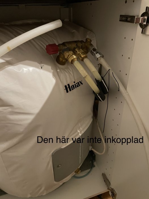 Varmvattenberedare (märkt "Høiax")  med rör och ventiler, i skåp, ej inkopplad, text "Den här var inte inkopplad".