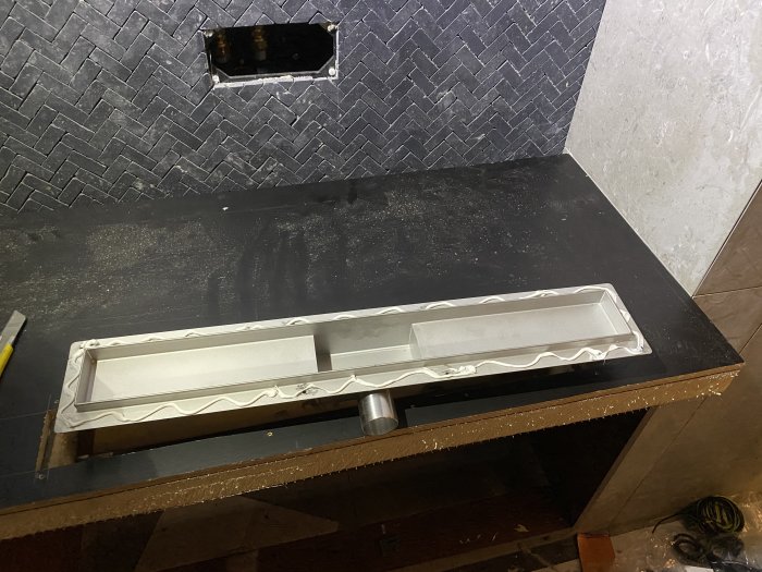 Installation av handfat på ett badrum med kakel och bänkskiva, renoveringsarbete pågår.