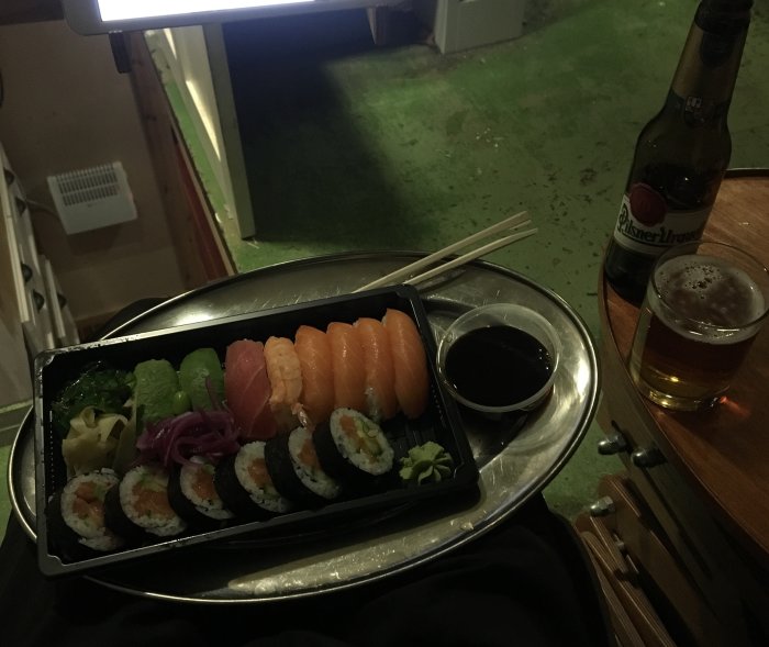 Sushimåltid med nigiri, maki, sojasås, wasabi, ingefära, ölflaska och glas.