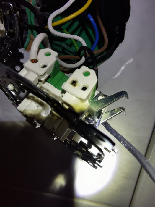 Öppen elektrisk installation med synliga kablar och anslutningar, risk för elektriska fel eller skador.