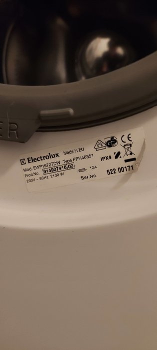 Produktskylt för Electrolux-apparat, modell och serienummer synliga, grå bakgrund, del av apparaten ser ut.