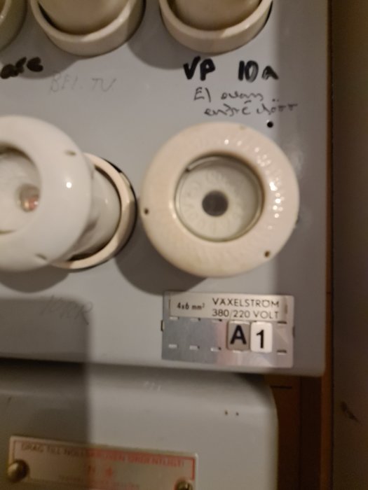 Äldre elcentral med säkringar, märkningar, 380/220 volt indikation. Otydlig fokusering och belysning.