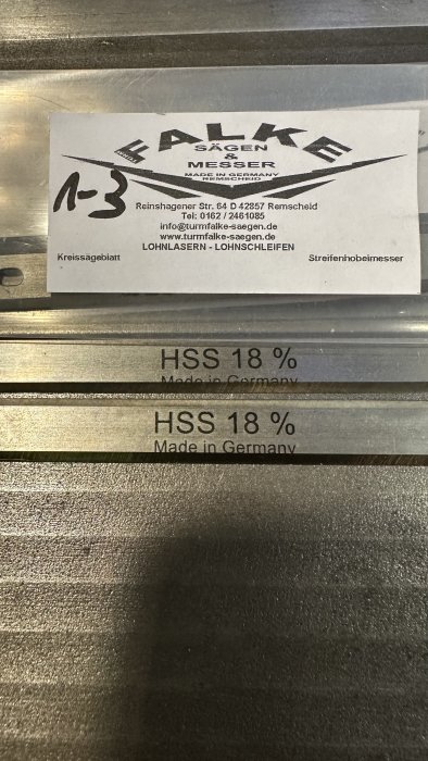 Metalliska objekt märkta "HSS 18%", "Made in Germany" och etikett från företaget "FALKE SÄGEN MESSER".