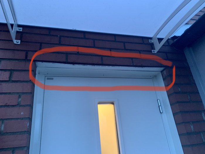 En dörr med överliggande tegelvägg markerad med en orange linje, antyder troligen en anmärkning eller ett problem.