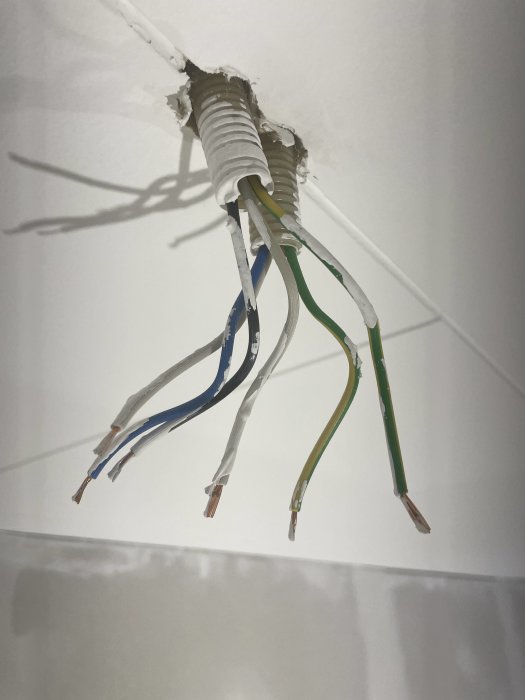 Öppen elektrisk installation med bar koppartråd ur tak, risk för elolycka, bör åtgärdas av elektriker.