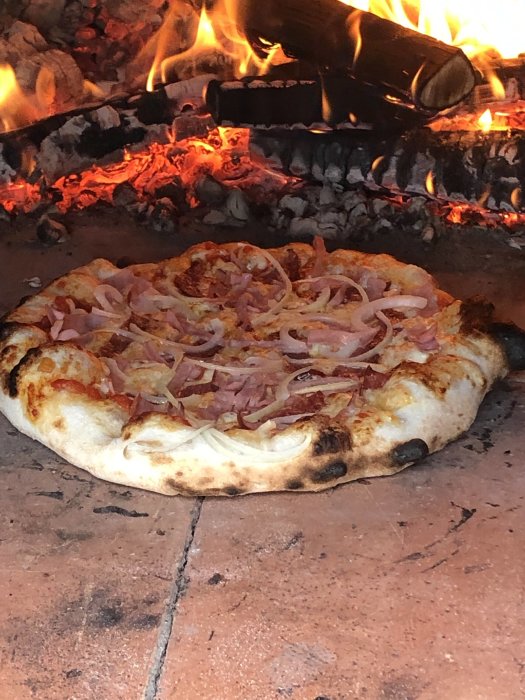 Pizza i vedeldad ugn, glödande kol, flammor, skinka, ost, matlagning, traditionell italiensk.