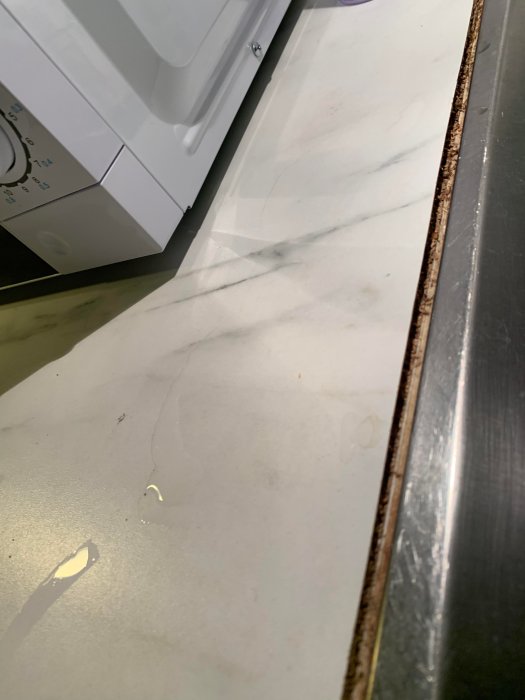 Marble countertop with a microwave, showing signs of wear and stains.