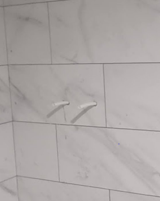 Två vita tandpetare på ett marmorerat kakelgolv.