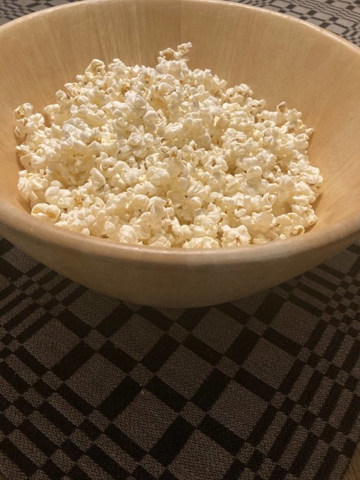 Stor träskål med popcorn, randig duk i bakgrunden, snack till filmkväll.