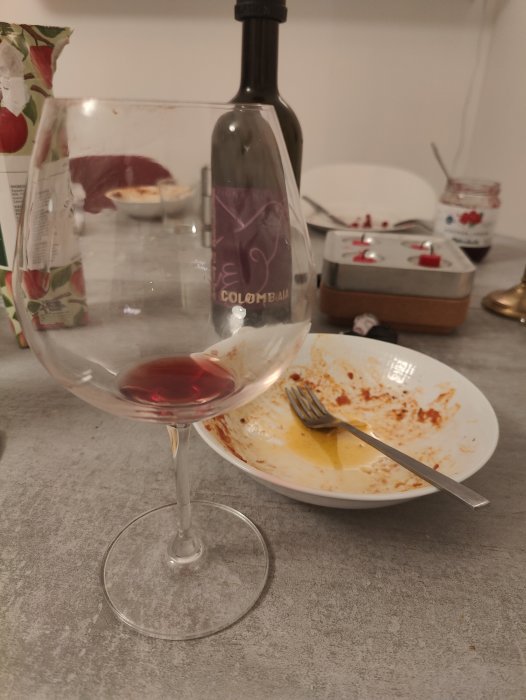 Eftermiddag med vin och mat; tomma smutsiga tallrikar och glas på köksbänken, använda servetter, mysig stämning.