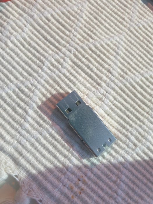 USB-minne på textil med ribbat mönster, ljusinsläpp i övre högra hörnet.
